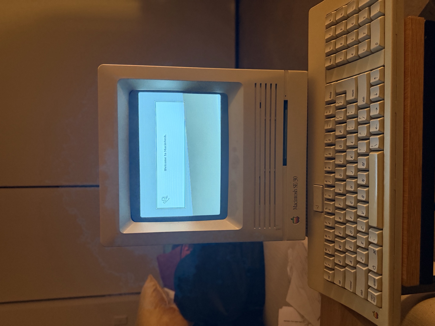 A restored Macintosh SE/30 and keyboard showing the Welcome to Macintosh screen